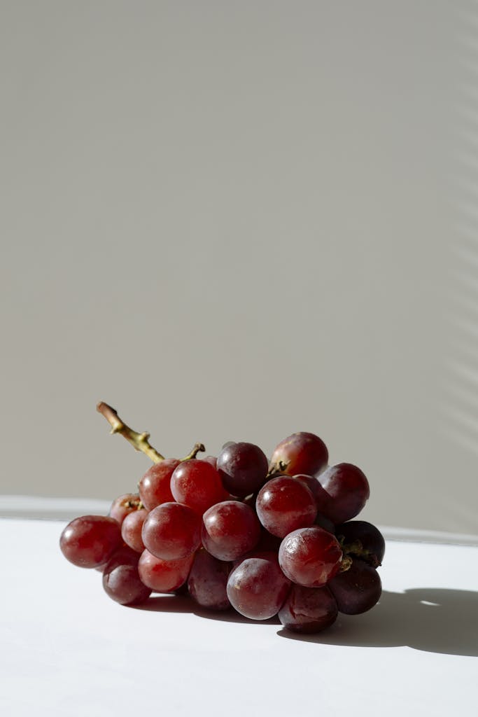 A bunch of red grapes in a minimalist setting with natural light.