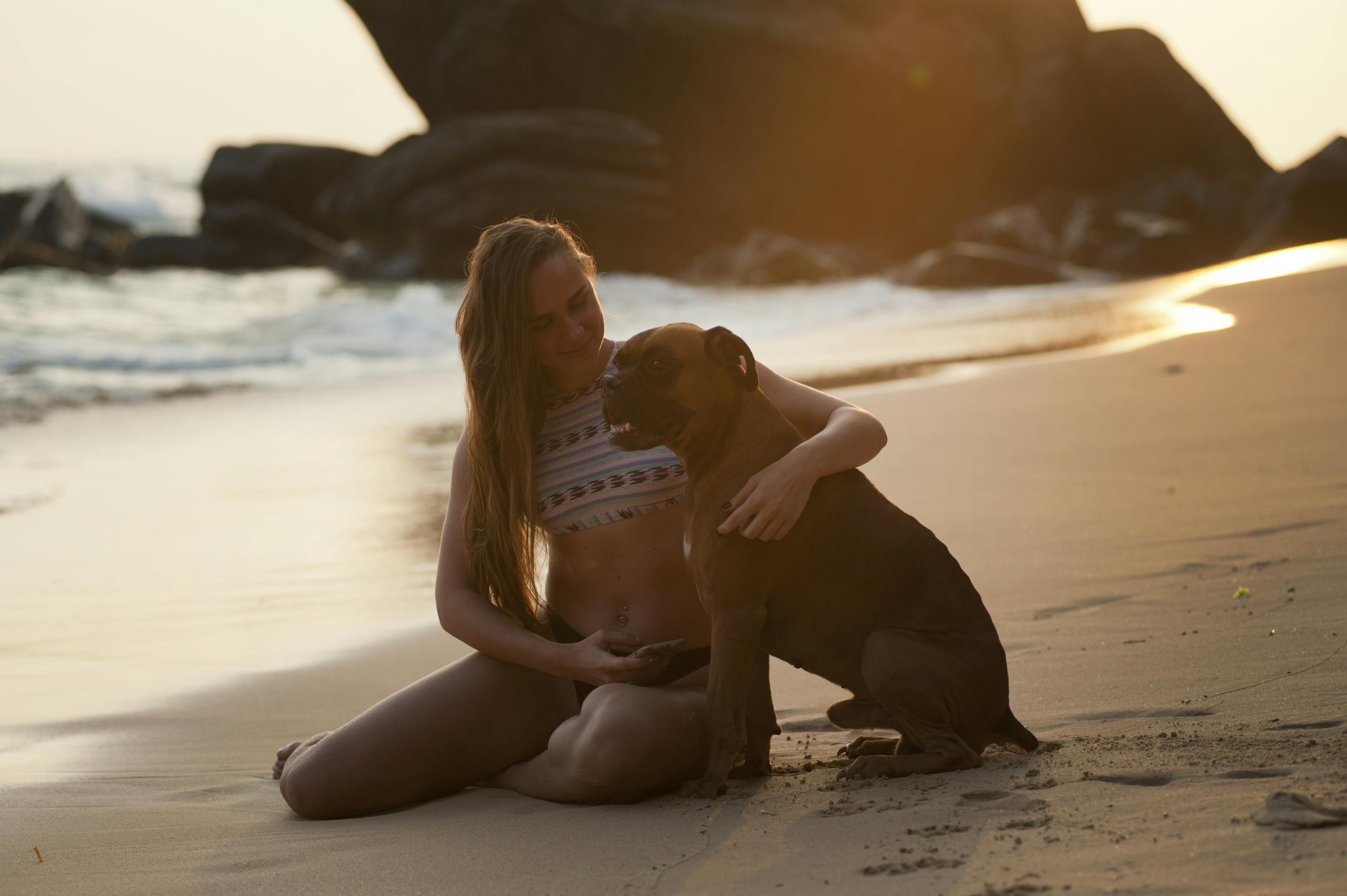 A woman and her dog enjoying a warm sunset together on Unawatuna Beach, Sri Lanka.