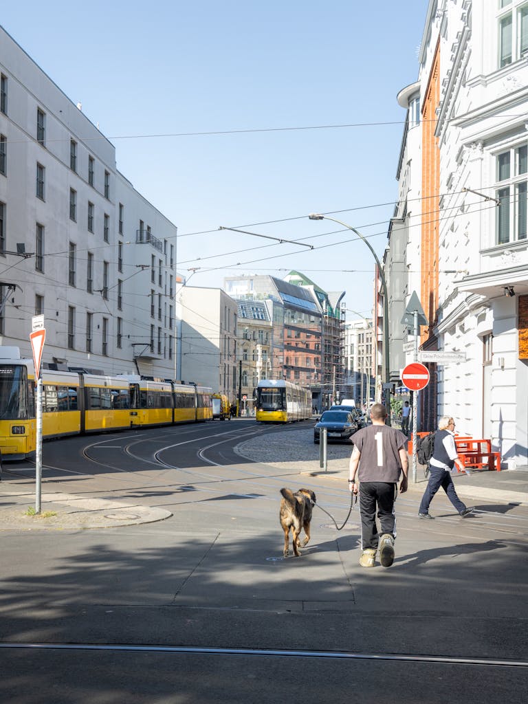 Busy street in Berlin featuring a tram, pedestrians, and urban architecture.