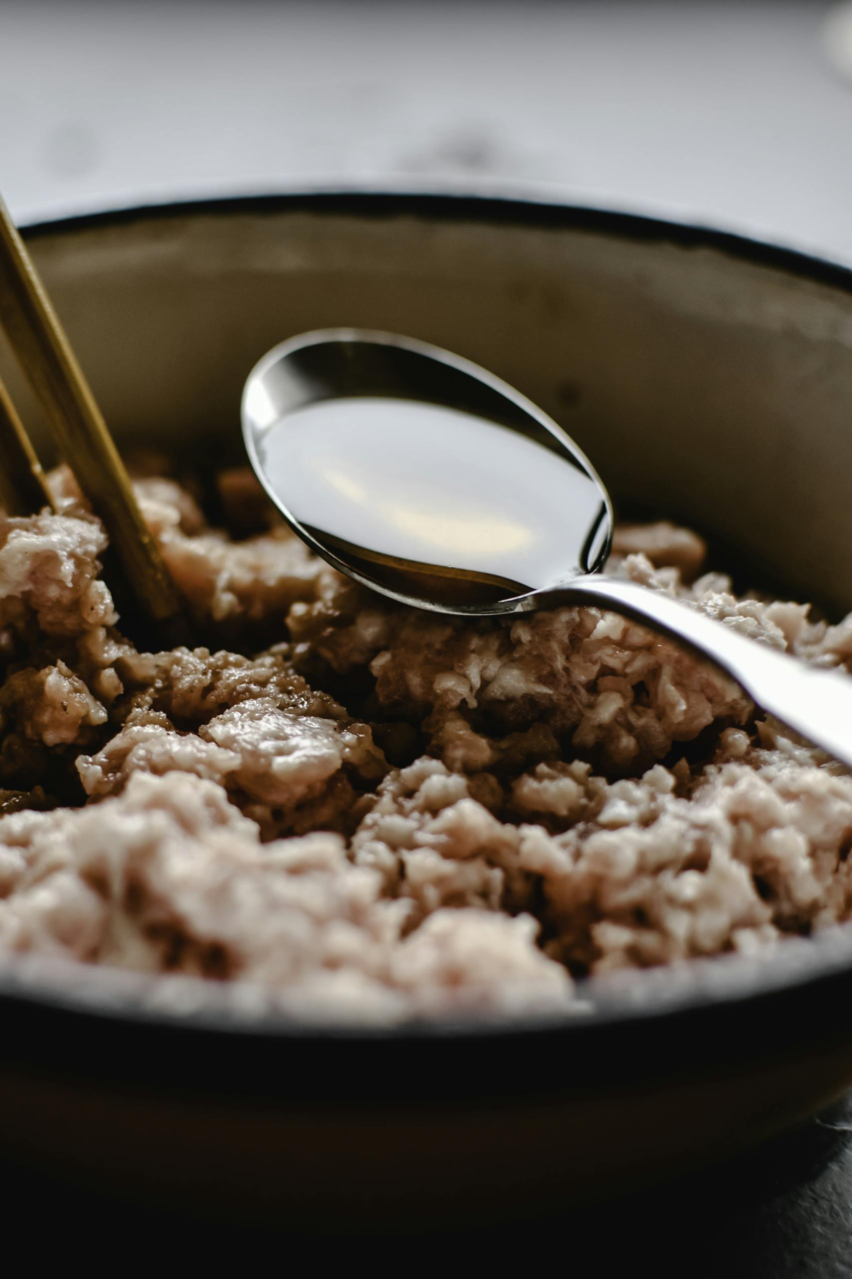 Delicious uncooked minced pork in a bowl with chopsticks and spoon, perfect for food prep.
