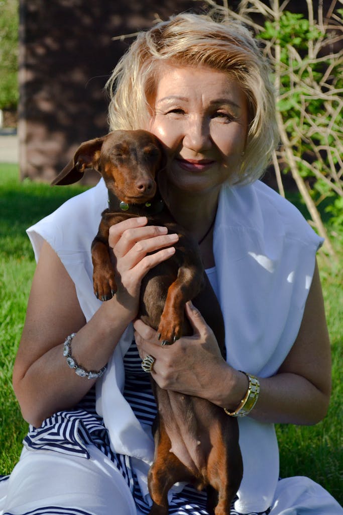Elderly woman enjoying sunny day with her dachshund in a park.