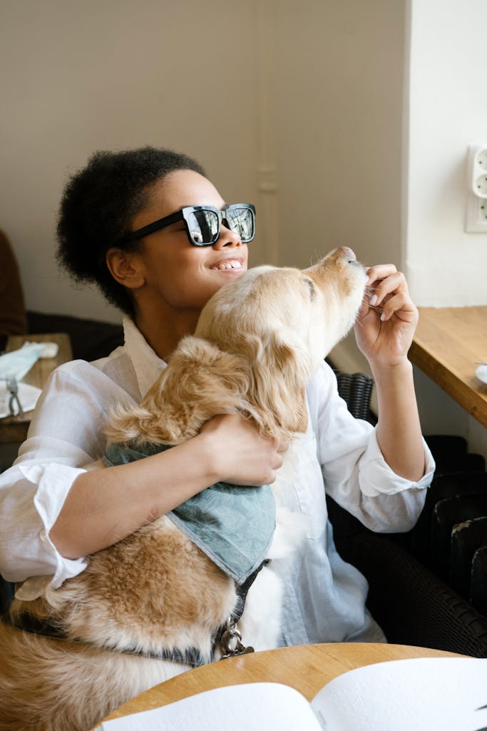 Smiling woman with visual impairment enjoying a moment with her guide dog at a cafe.